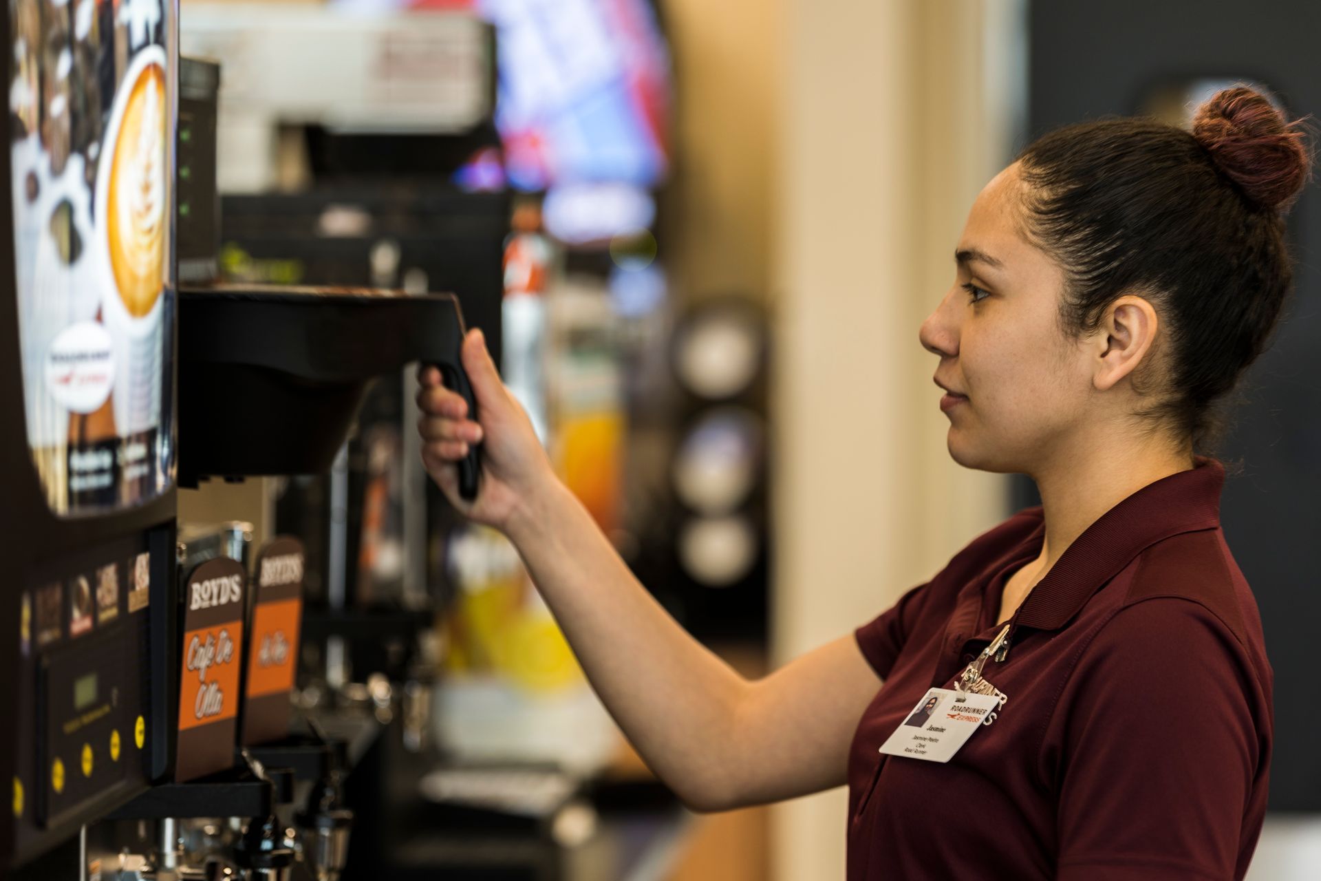 A woman is using a coffee machine in a restaurant.