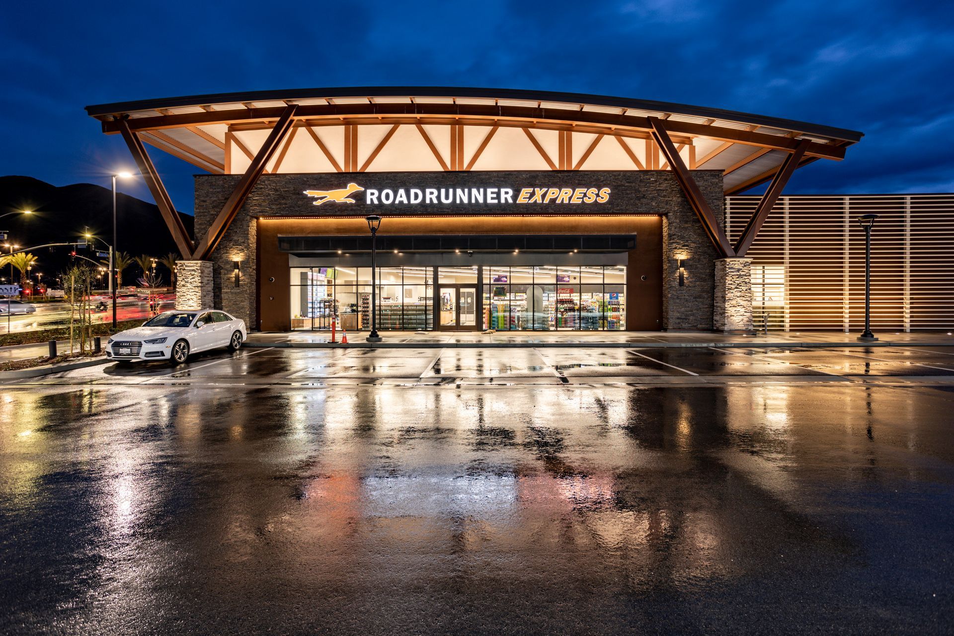 A white car is parked in front of a building that says roadrunner express