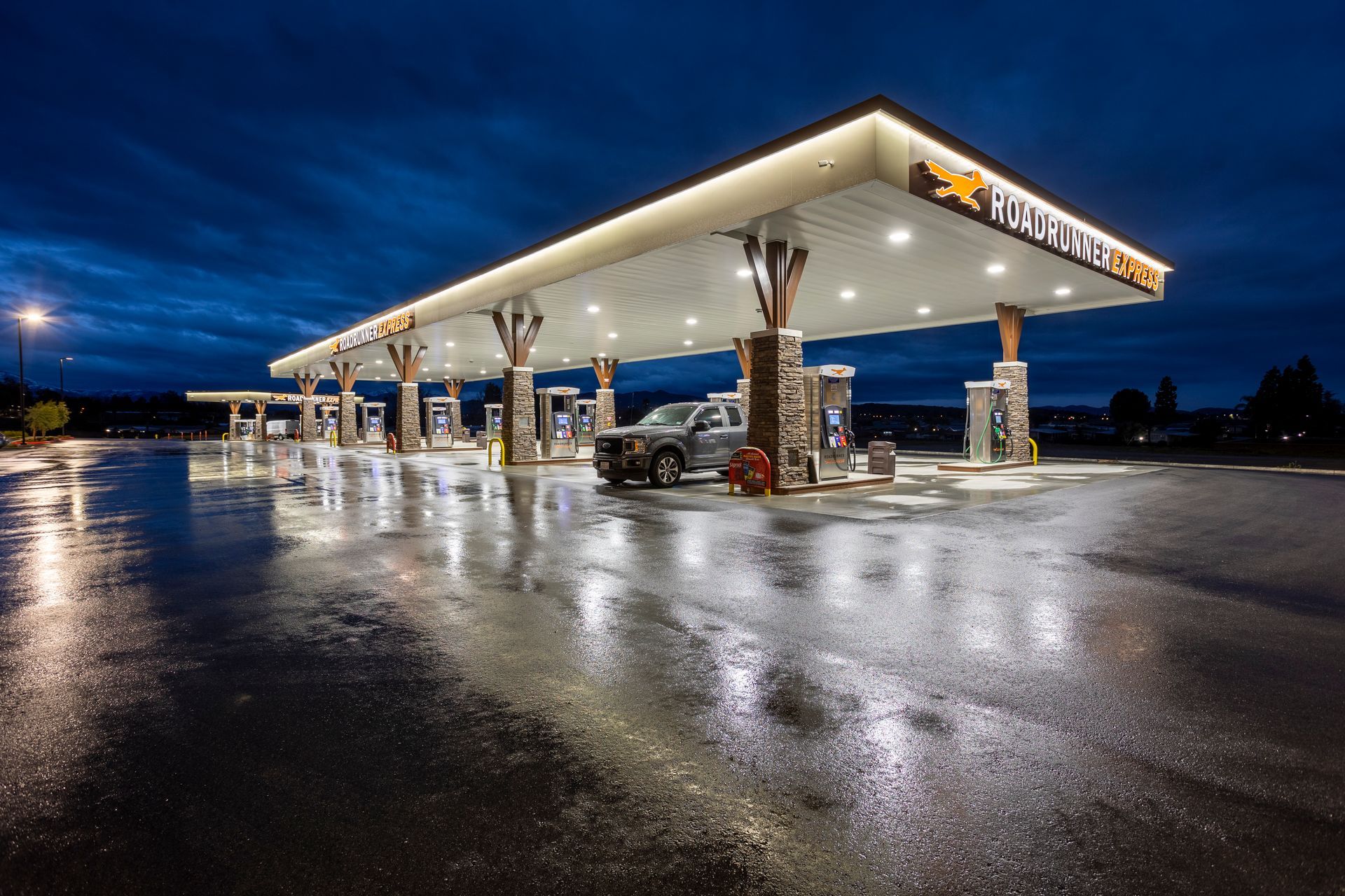 A car is parked at a gas station at night.