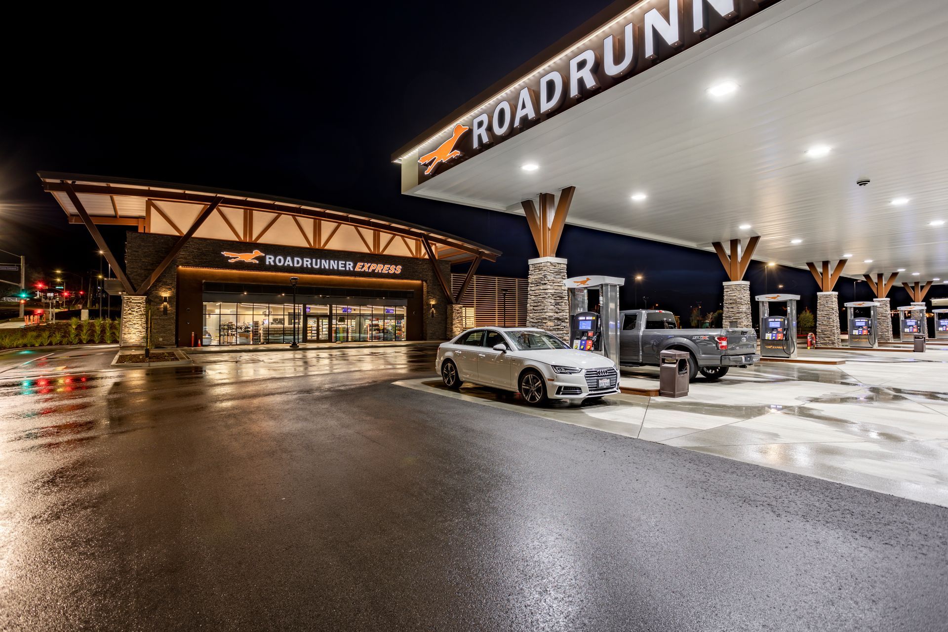 A car is parked in front of a gas station at night.