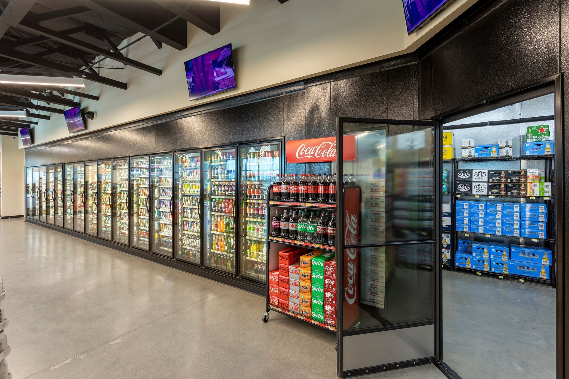 A row of refrigerators in a store with a coca cola display.