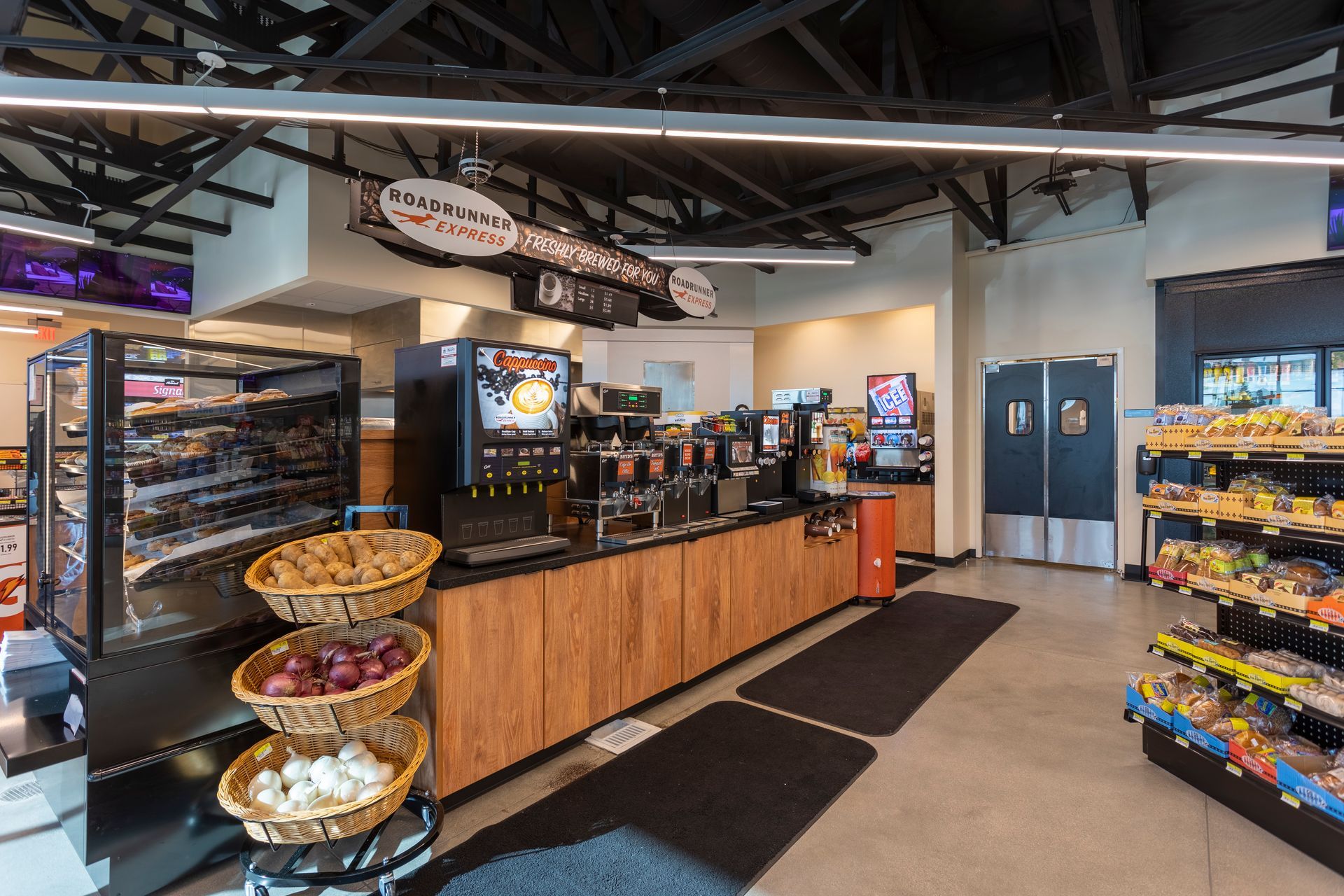 A convenience store with a counter and baskets of fruit and vegetables.