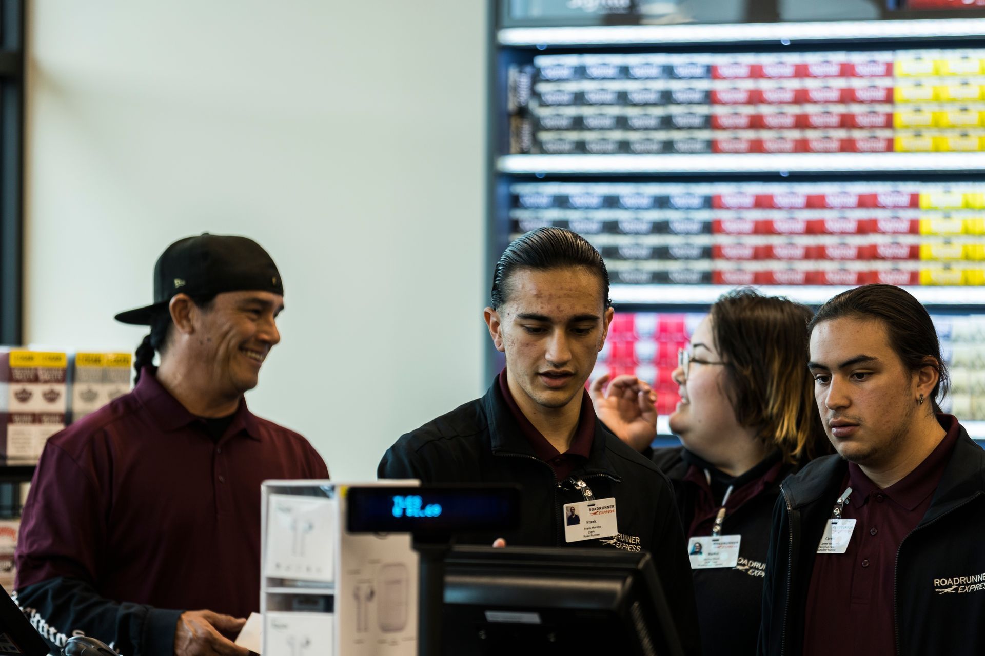 A group of people are standing around a cash register in a store.