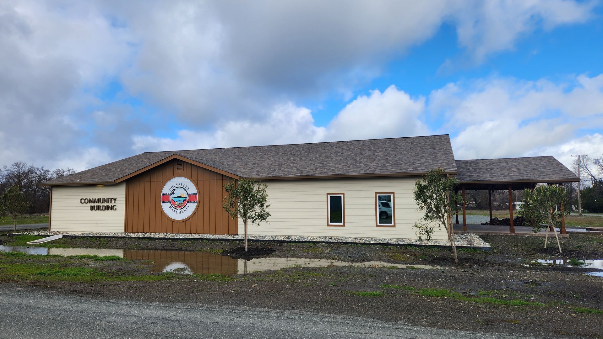 A large white building with a brown roof is sitting in the middle of a flooded field.