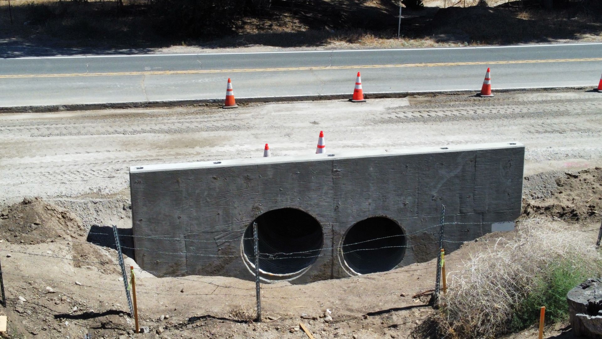A concrete block with two holes in it sits on the side of a road