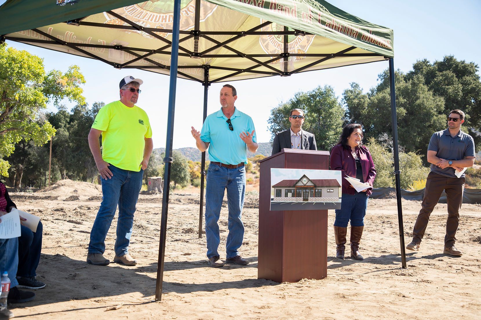 A group of people standing around a podium under a tent.