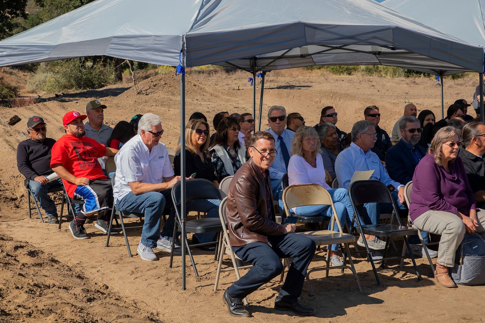 A group of people are sitting under a tent in the desert.
