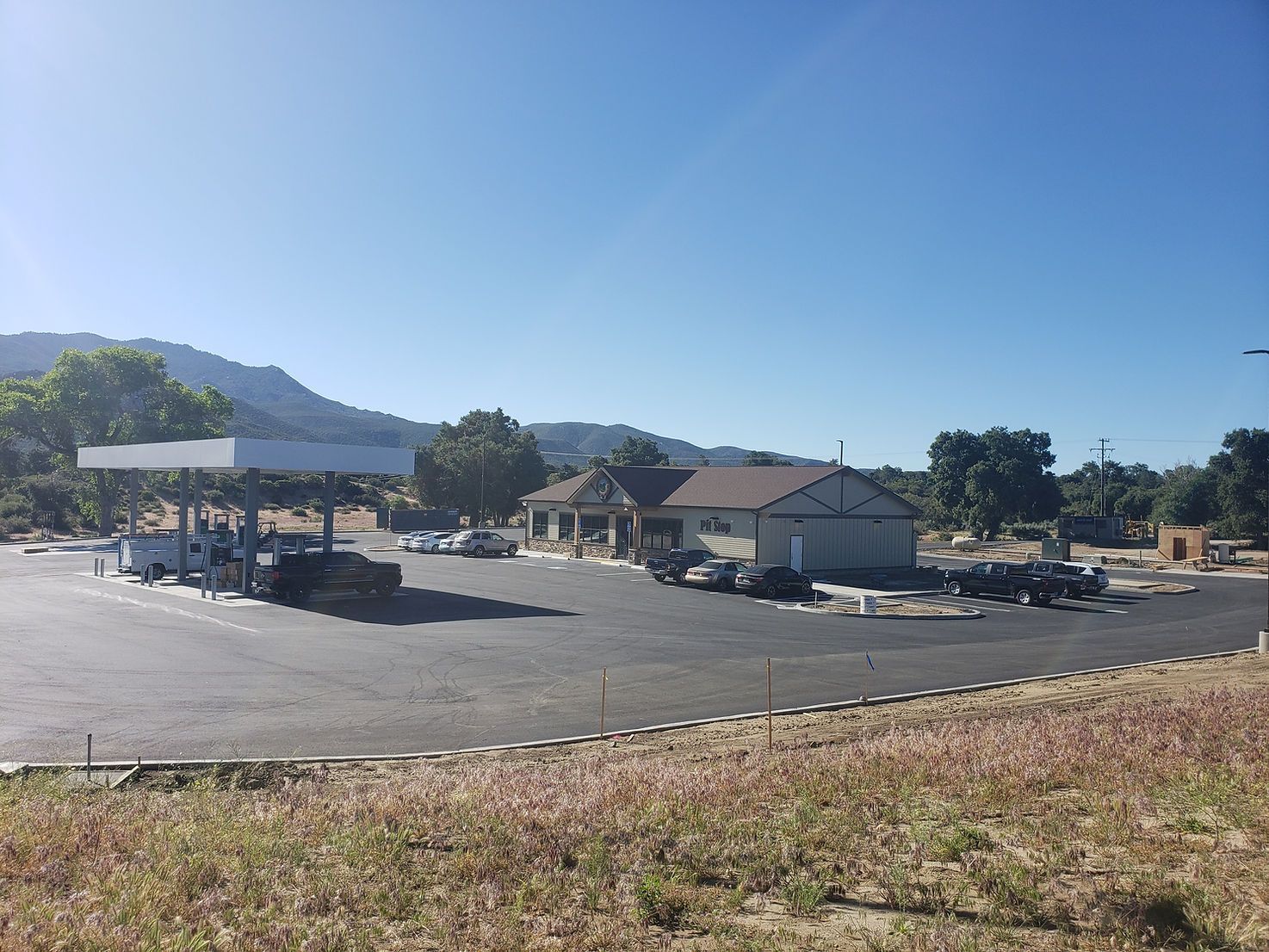 A gas station with cars parked in front of it on a sunny day.