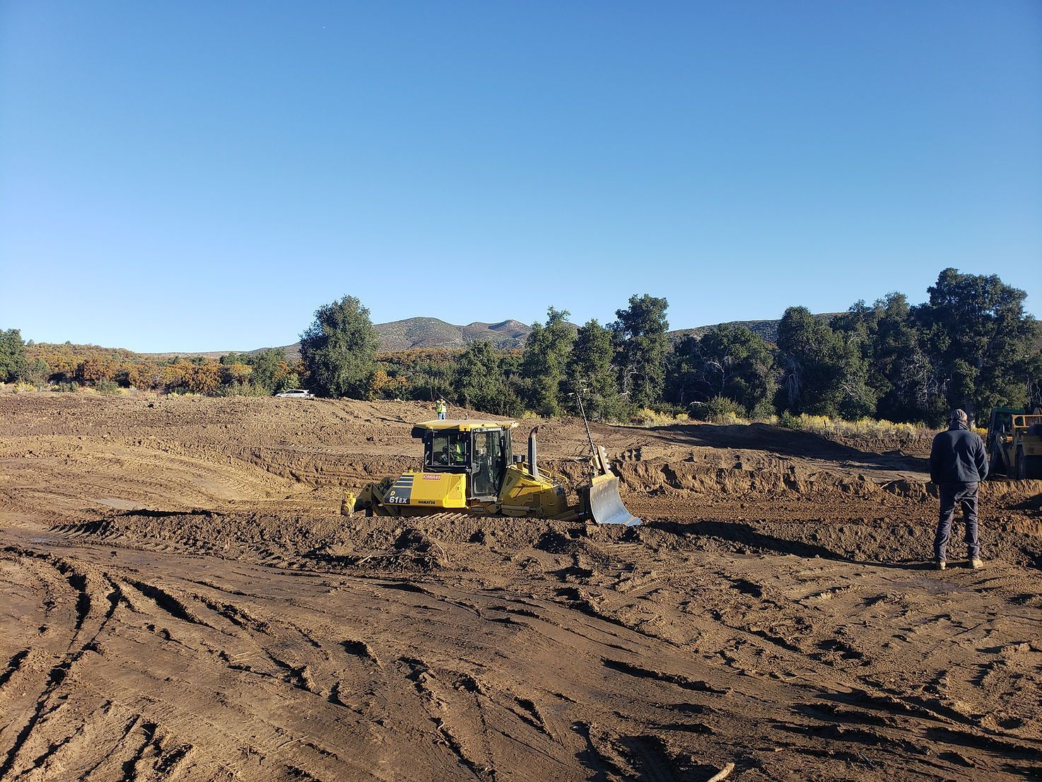 A bulldozer is sitting in the middle of a dirt field.