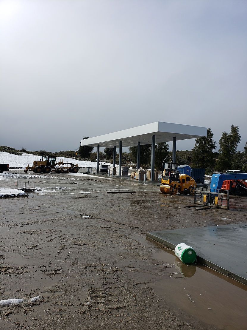 A muddy field with a gas station in the background.