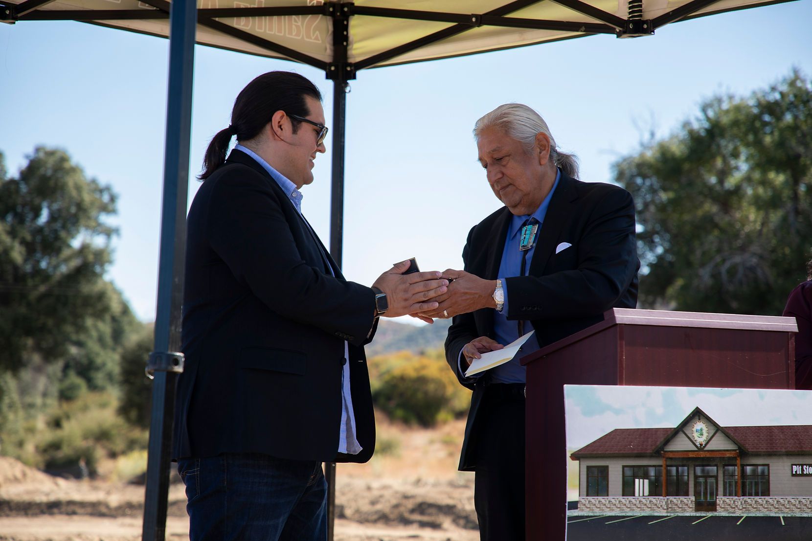 Two men are shaking hands in front of a podium.