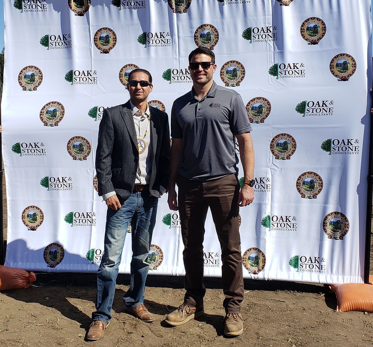 Two men are standing in front of a backdrop that says oak point