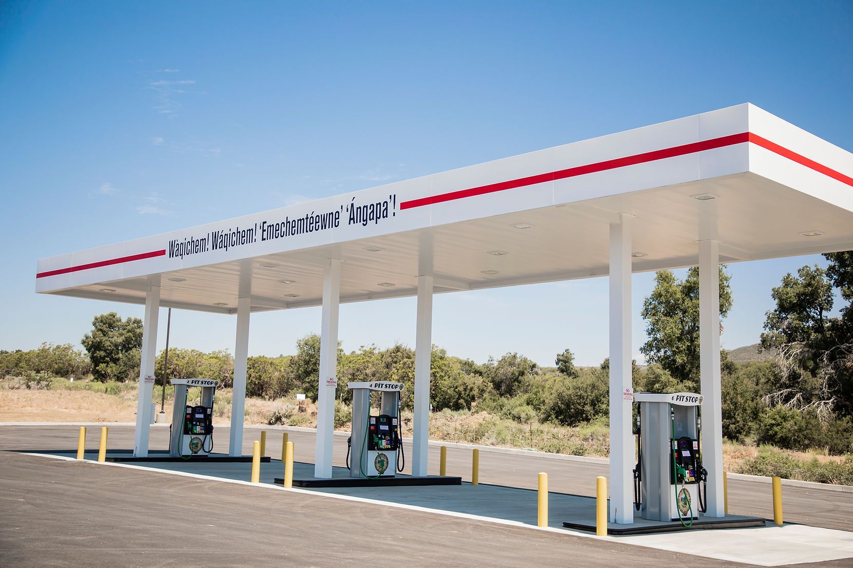A gas station with a canopy and pumps on a sunny day.