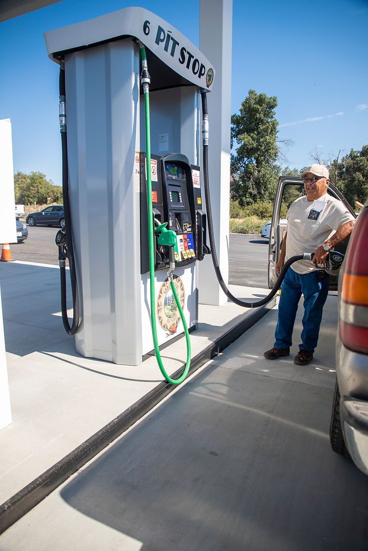 A man is pumping gas into a car at a gas station