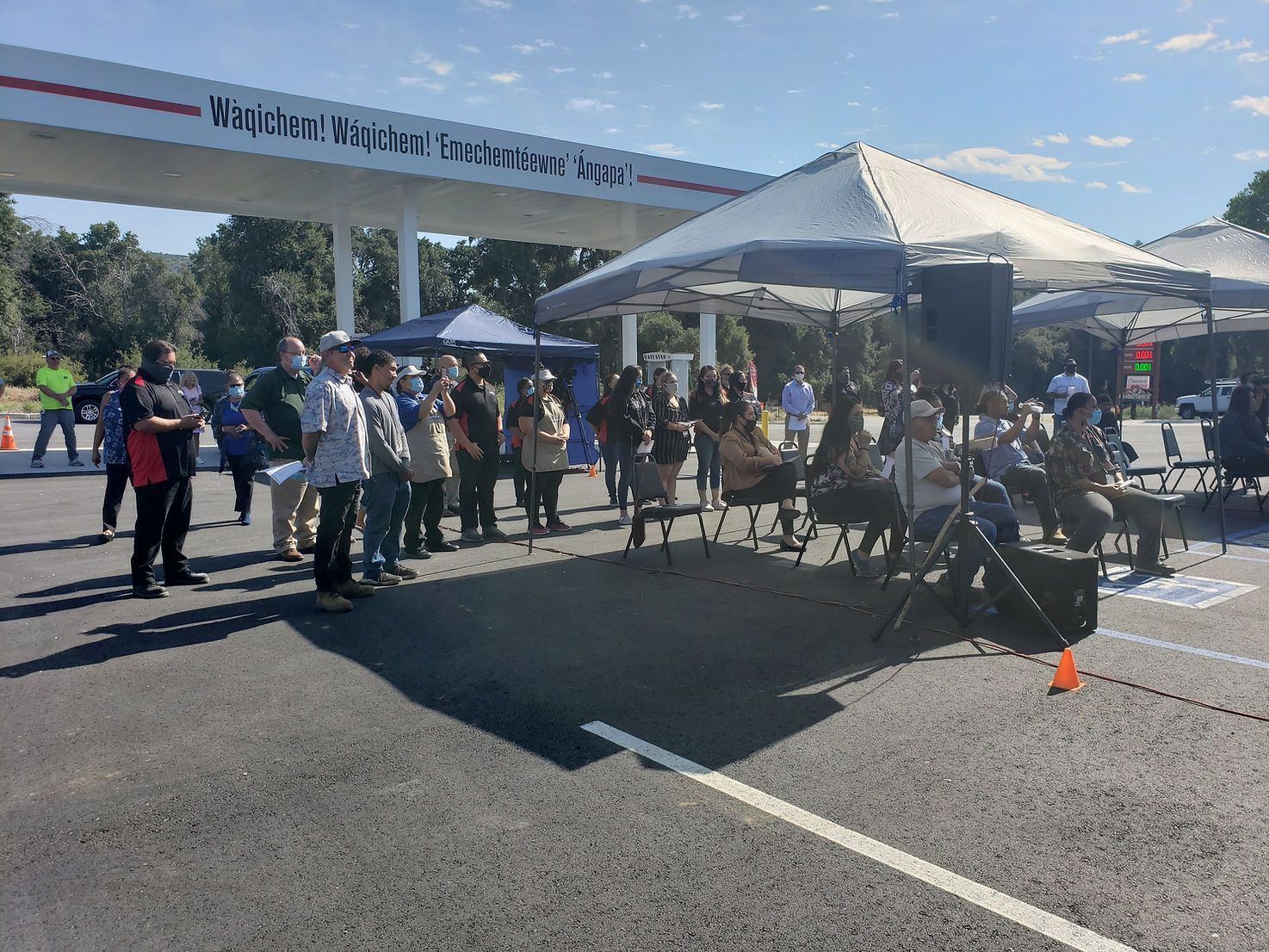 A group of people are standing under tents in a parking lot.