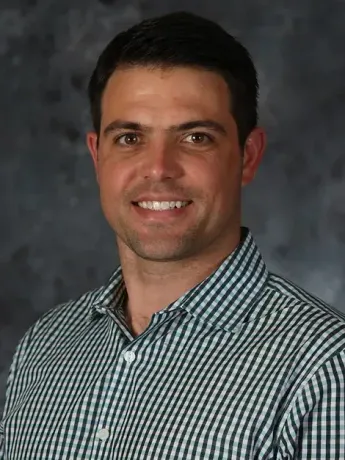 A man in a plaid shirt is smiling for the camera.