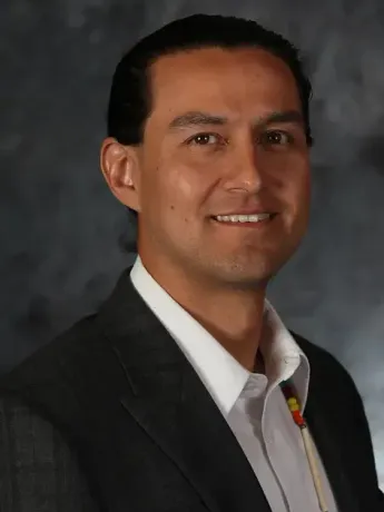 A man in a suit and white shirt is smiling for the camera.