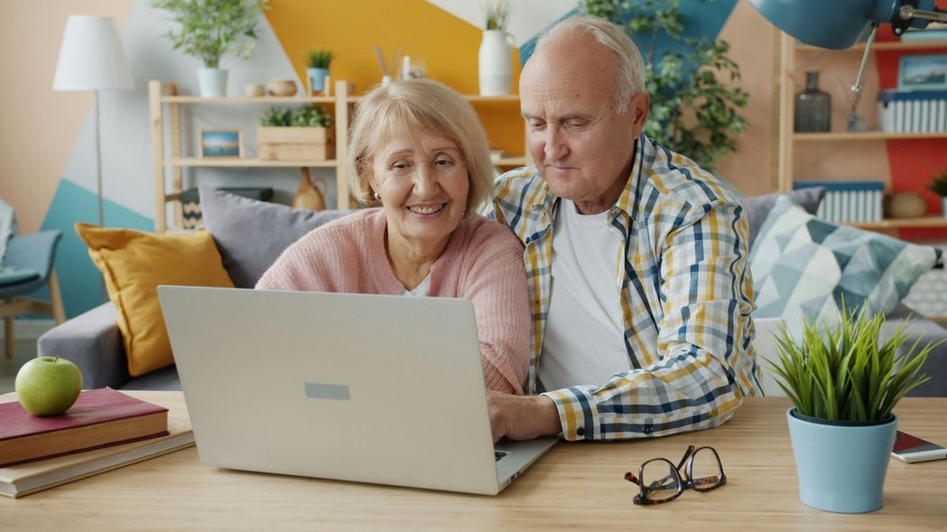 Three people looking at a tablet and papers on a table, discussing work. Indoors, neutral colors.