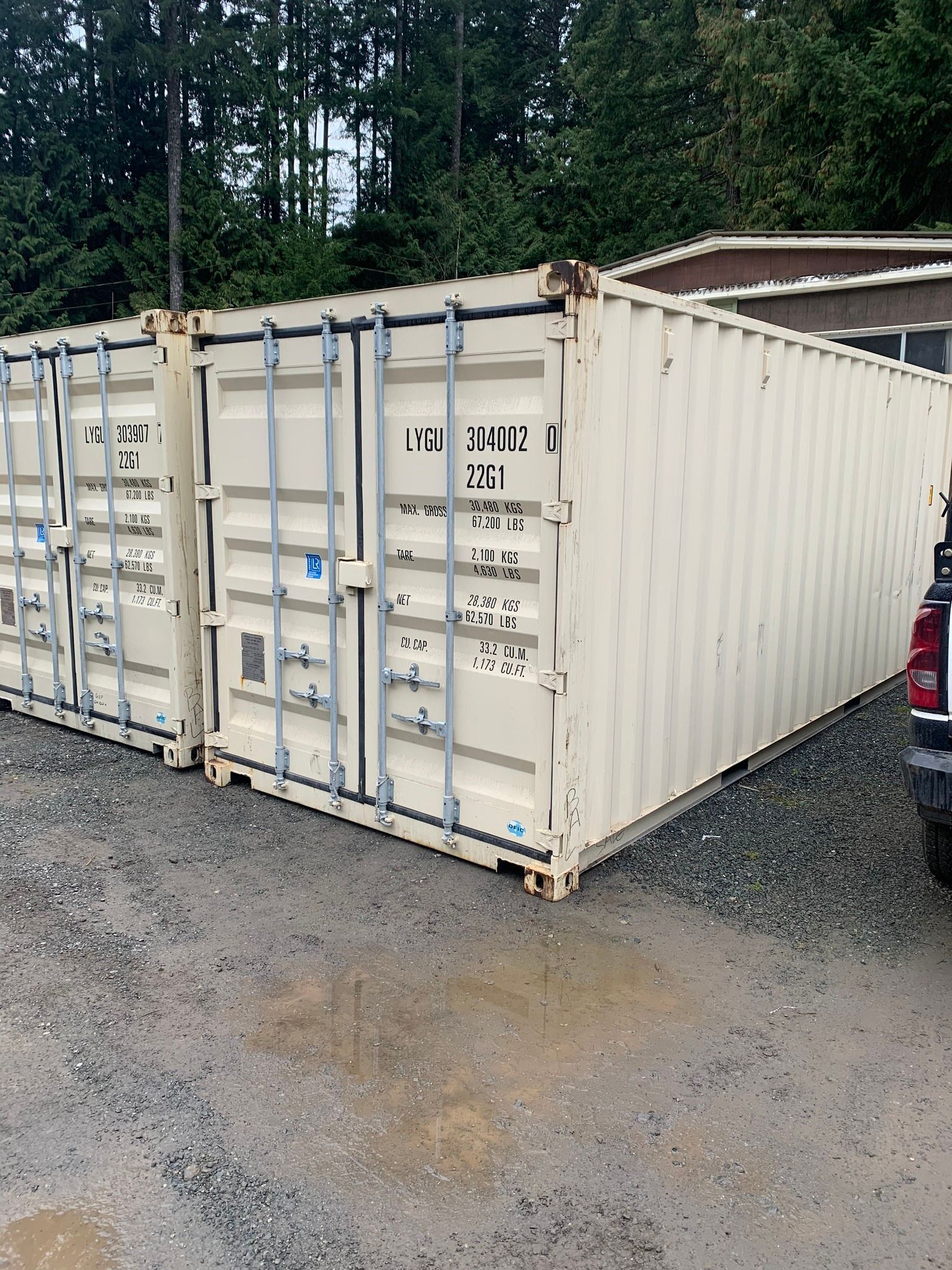 A row of shipping containers are parked next to each other in a gravel lot.