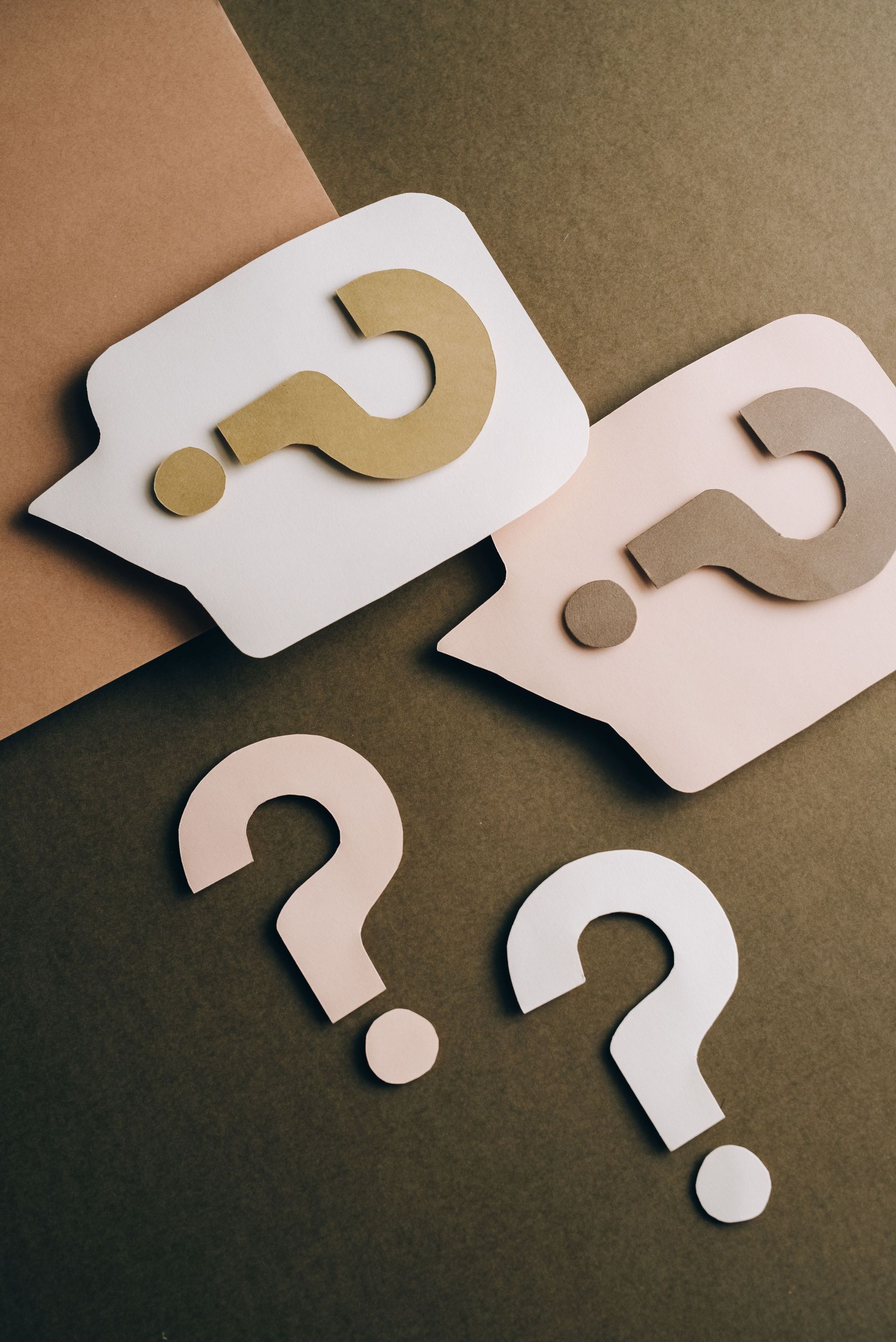 White and beige question mark icons scattered on a neutral background