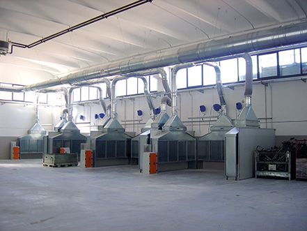 Industrial workshop with several large white metal machines arranged in a row inside a bright factory hall