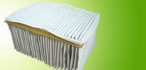 Pleated white air filter with tan frame on a green background