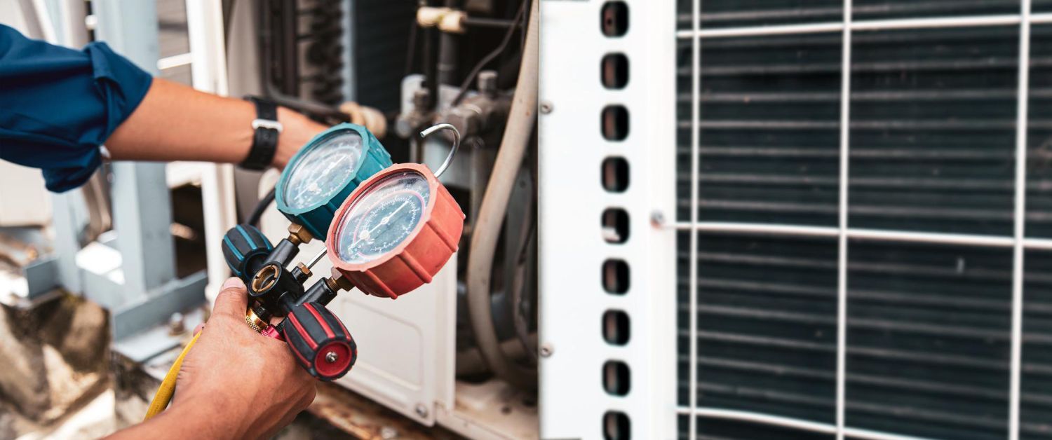 Technician uses a manifold gauge set to service the condenser unit of an outdoor air conditioning system.