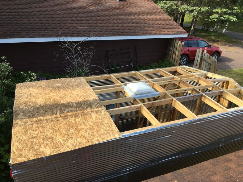Roof construction over a house with exposed wooden framing and plywood sheathing