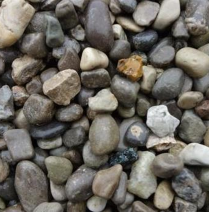 A close-up view of various small, smooth, multi-colored pebbles and river stones scattered together.