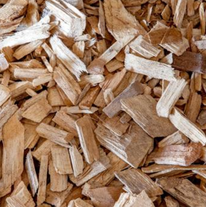 A close-up view of a pile of light-brown wood chips with varying shapes and textures.