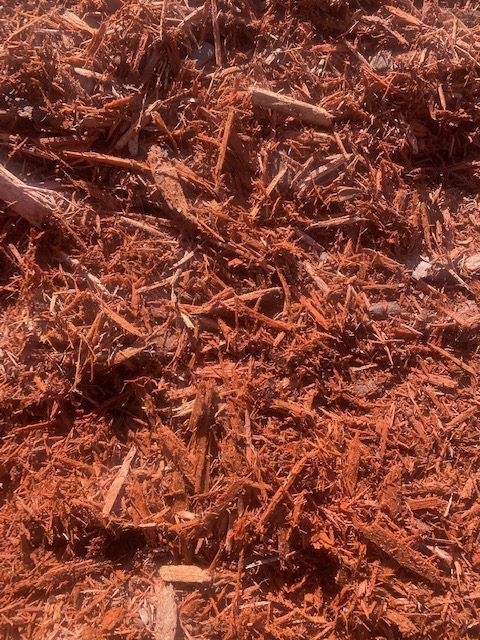 A close-up view of coarse, reddish-brown wood mulch covering the ground.