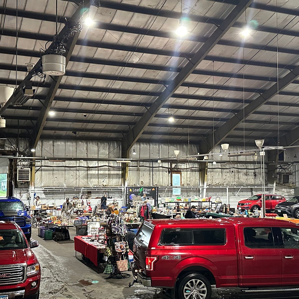 Indoor warehouse market with red trucks, stalls, and people under a high metal roof