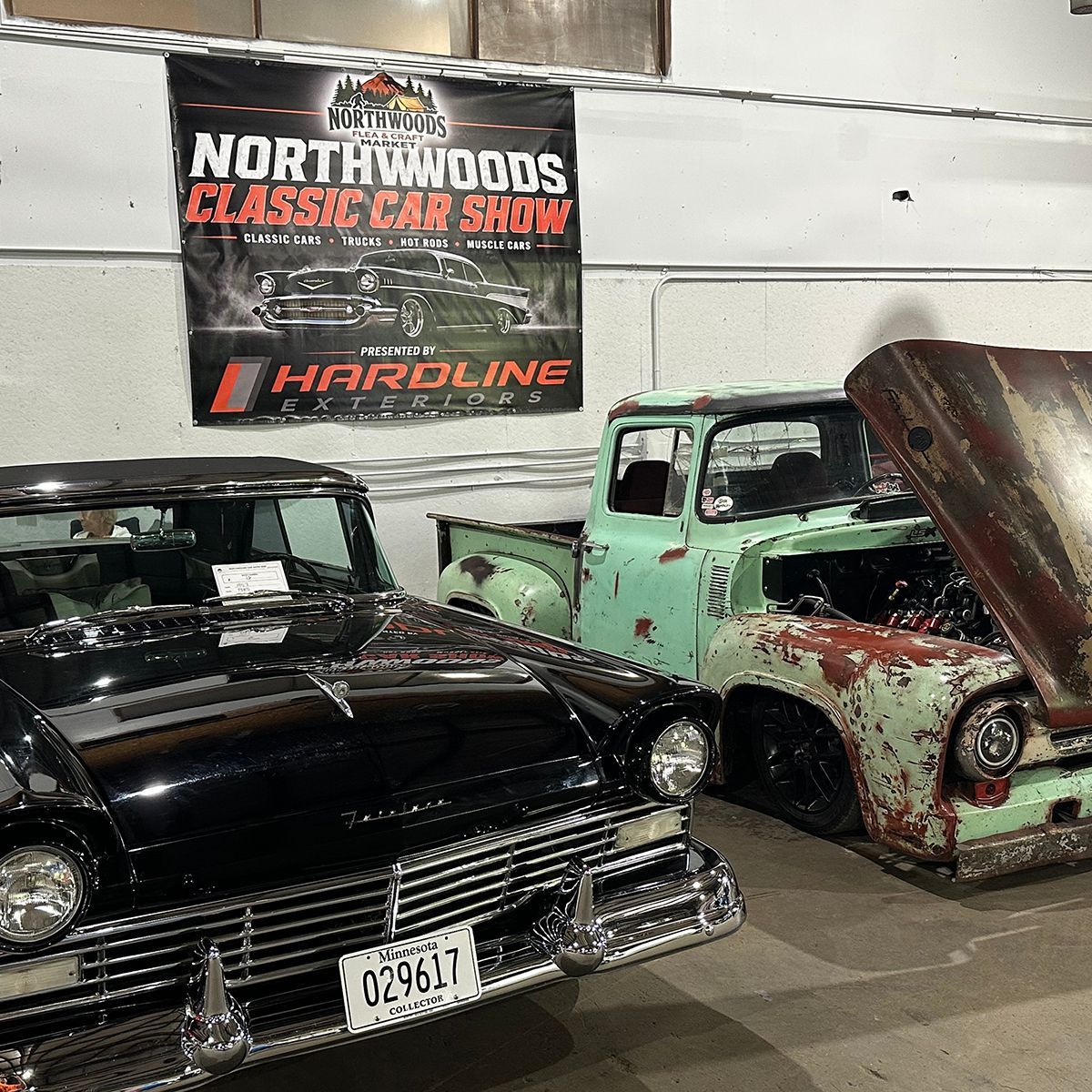 Classic car show with a black vintage car and a mint green pickup under a classic car show banner 