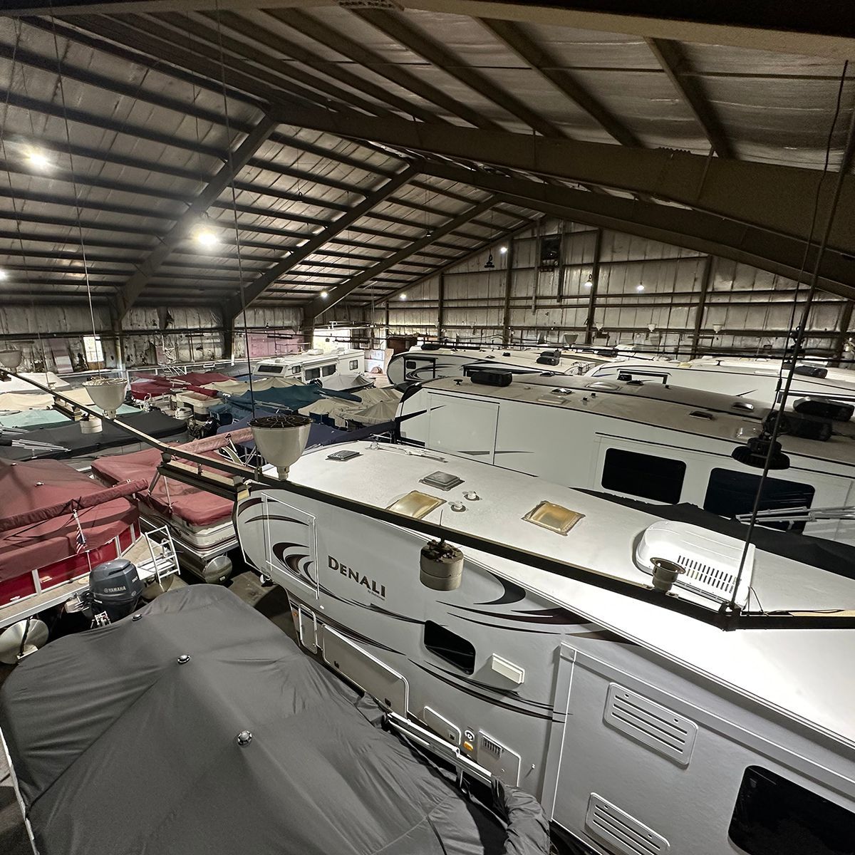 Indoor winter storage facility packed with boats and RVs under a high metal roof