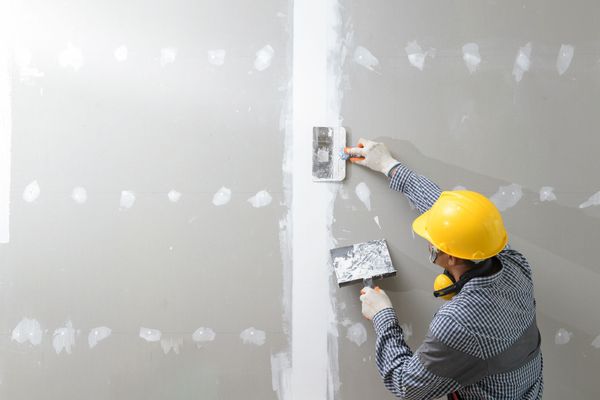 A man is plastering a wall with a spatula.