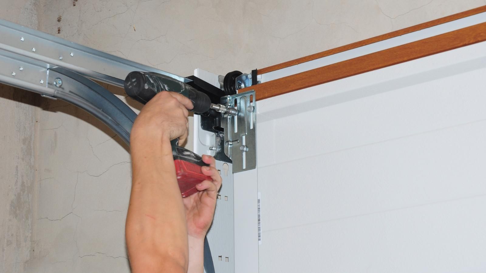 A technician is fixing a garage door with a drill.
