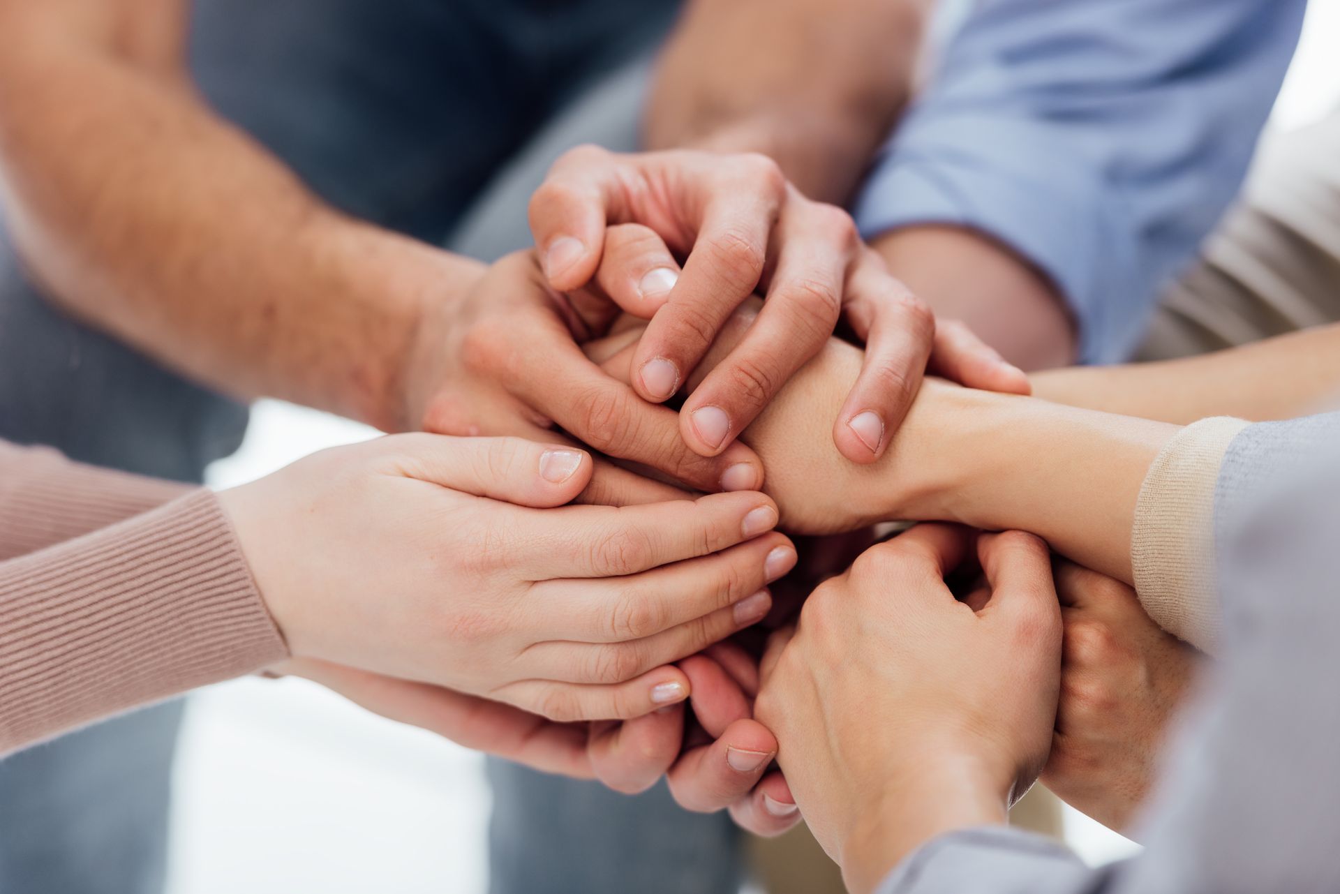 Hands of several people piled on top of each other in a symbol of teamwork and unity. Hands of several people piled on top of each other in a symbol of teamwork and unity.
