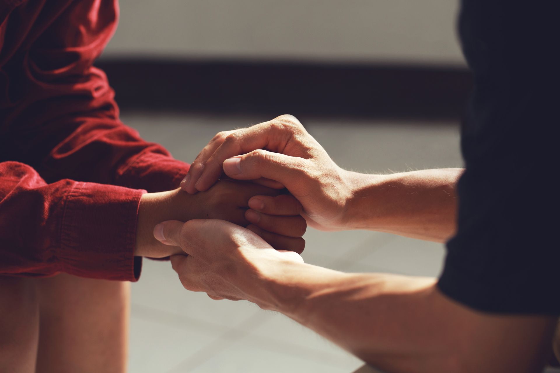 Two hands clasped, one person's hand resting in the other's, offering support. Two hands clasped, one person's hand resting in the other's, offering support.