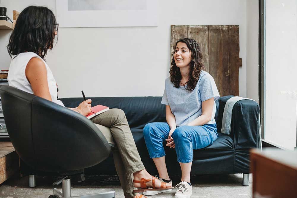 Woman smiles while talking to therapist in an office.