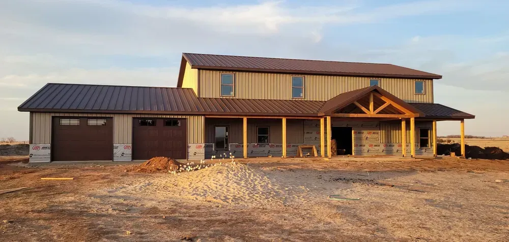A large house is being built in the middle of a dirt field.