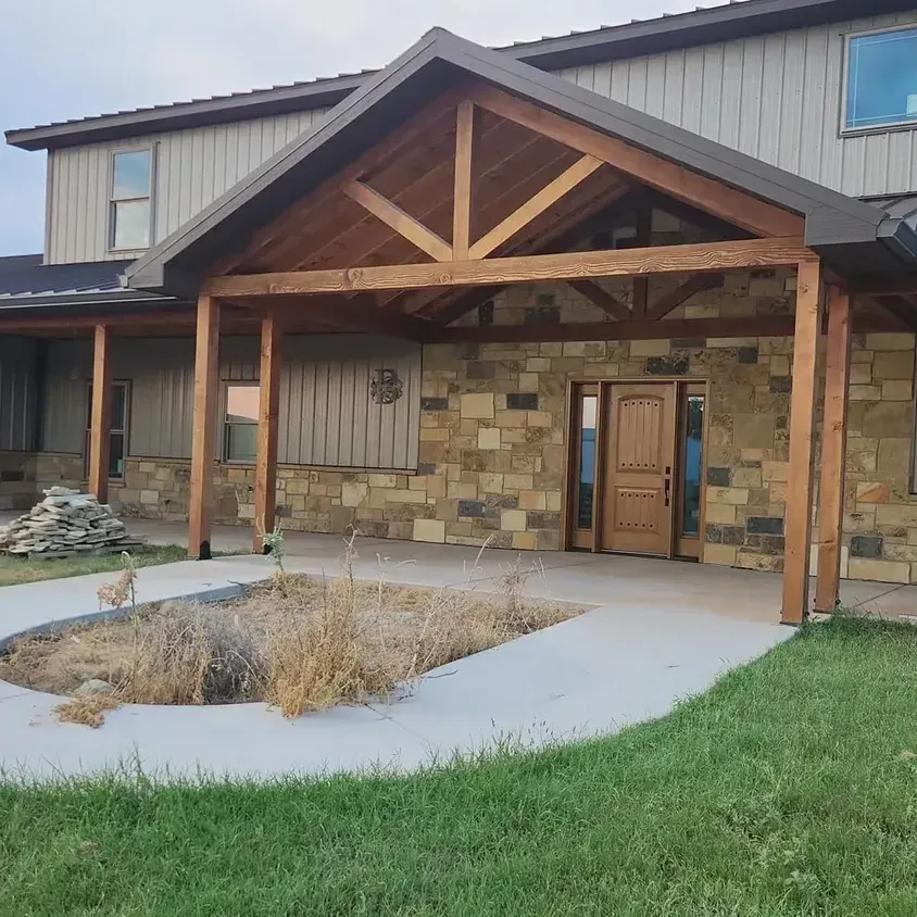A large house with a wooden porch and a fire pit in front of it.