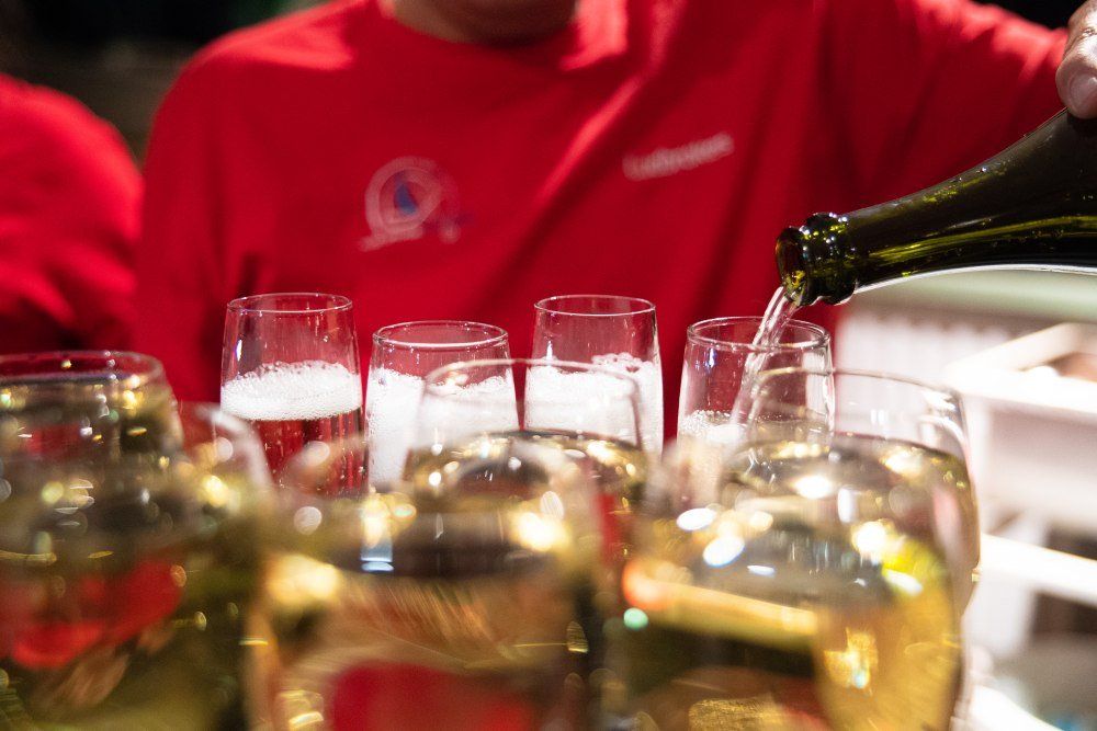 A man in a red shirt is pouring champagne into glasses.