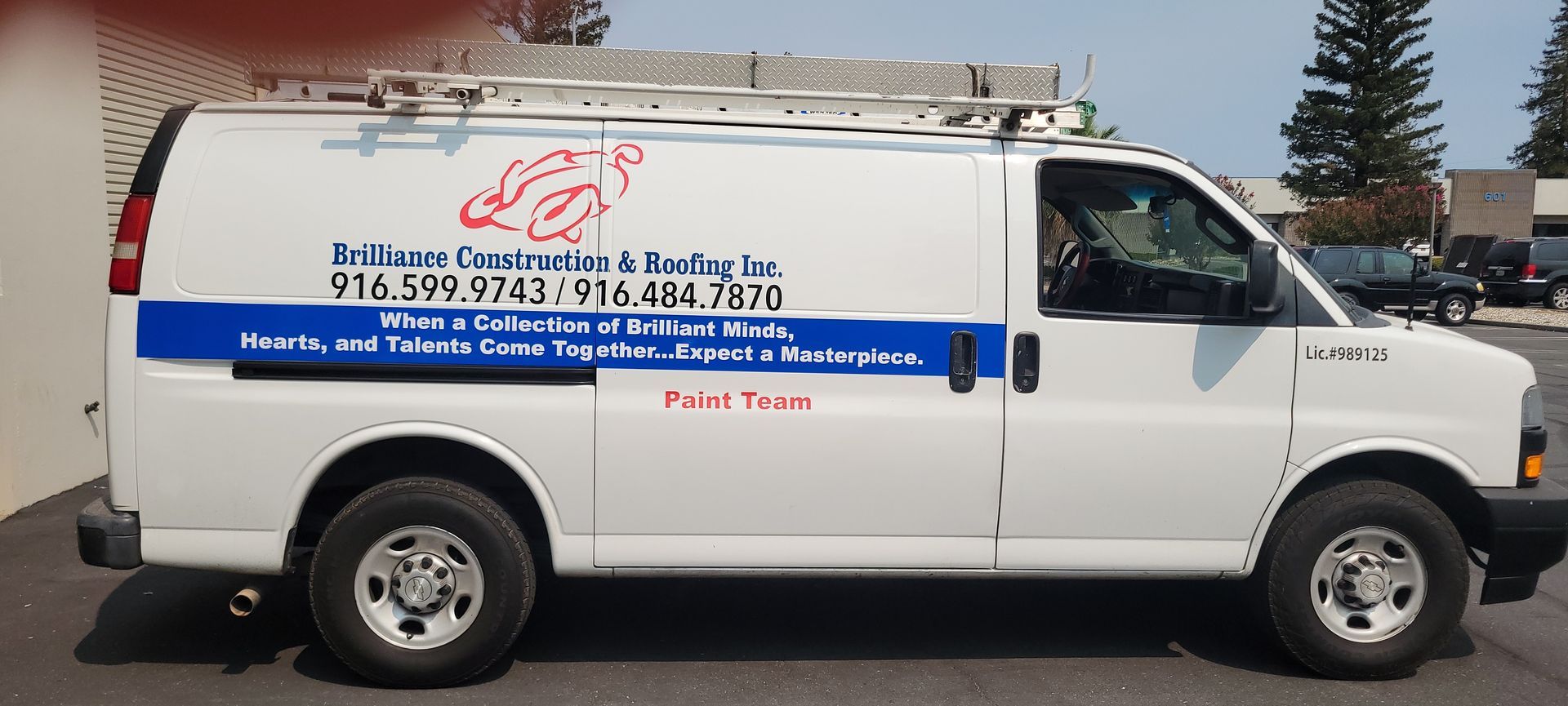White utility van with blue lettering and graphics parked outdoors on a street.