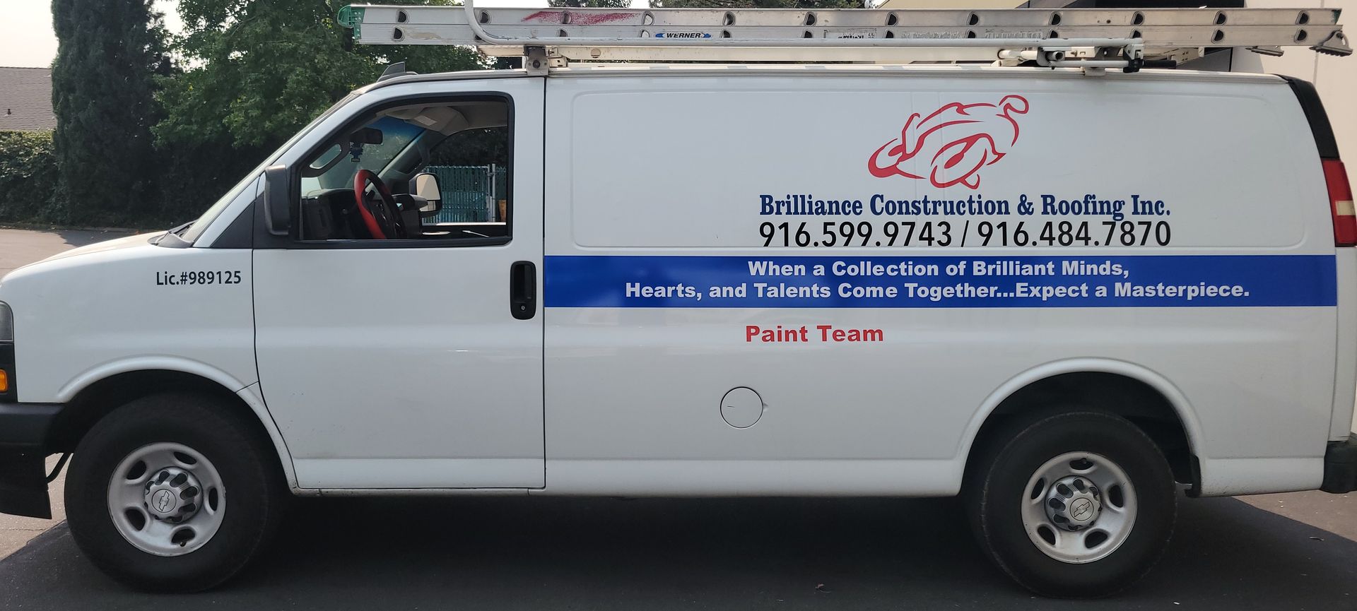 White service van with blue stripe and ladder rack, parked on a street with company contact info on the side