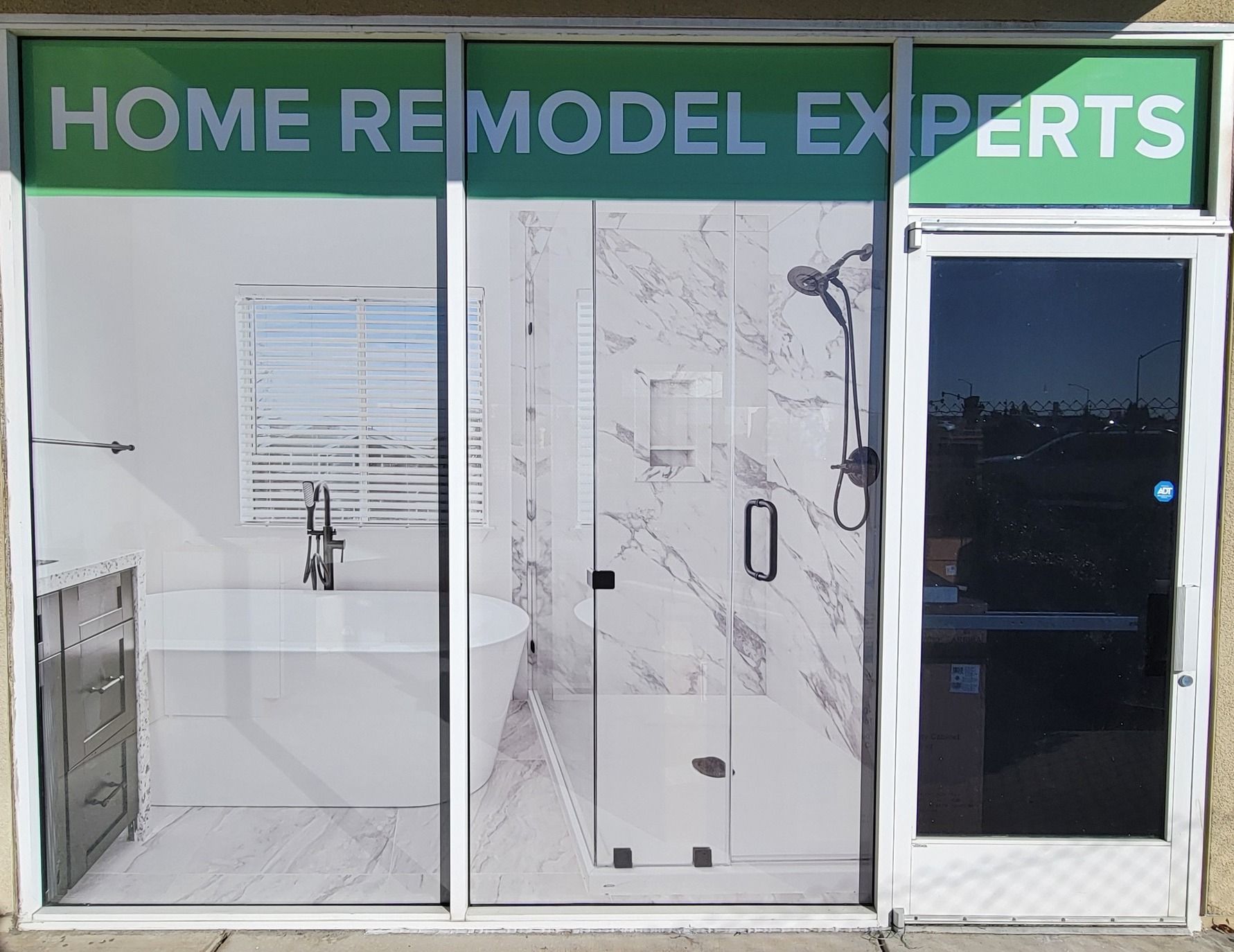 Storefront with “HOME REMODEL EXPERTS” sign and two display shower/tile bathrooms.
