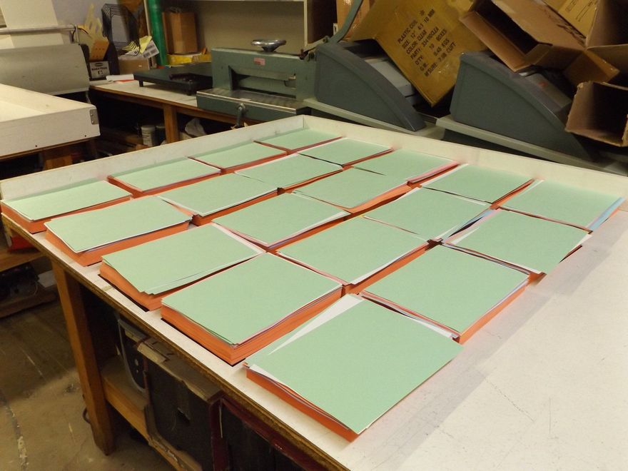 Green and orange rectangular objects arranged on a white table in a workshop setting.