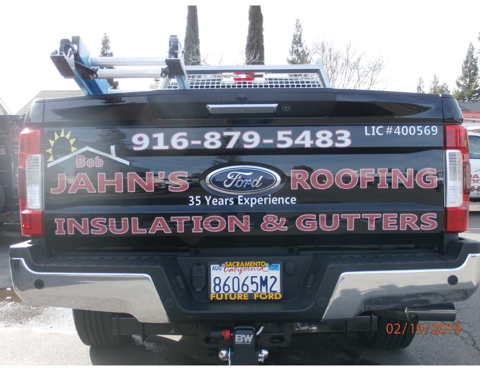 Black Ford truck with roofing business logo, phone number, and license plate.