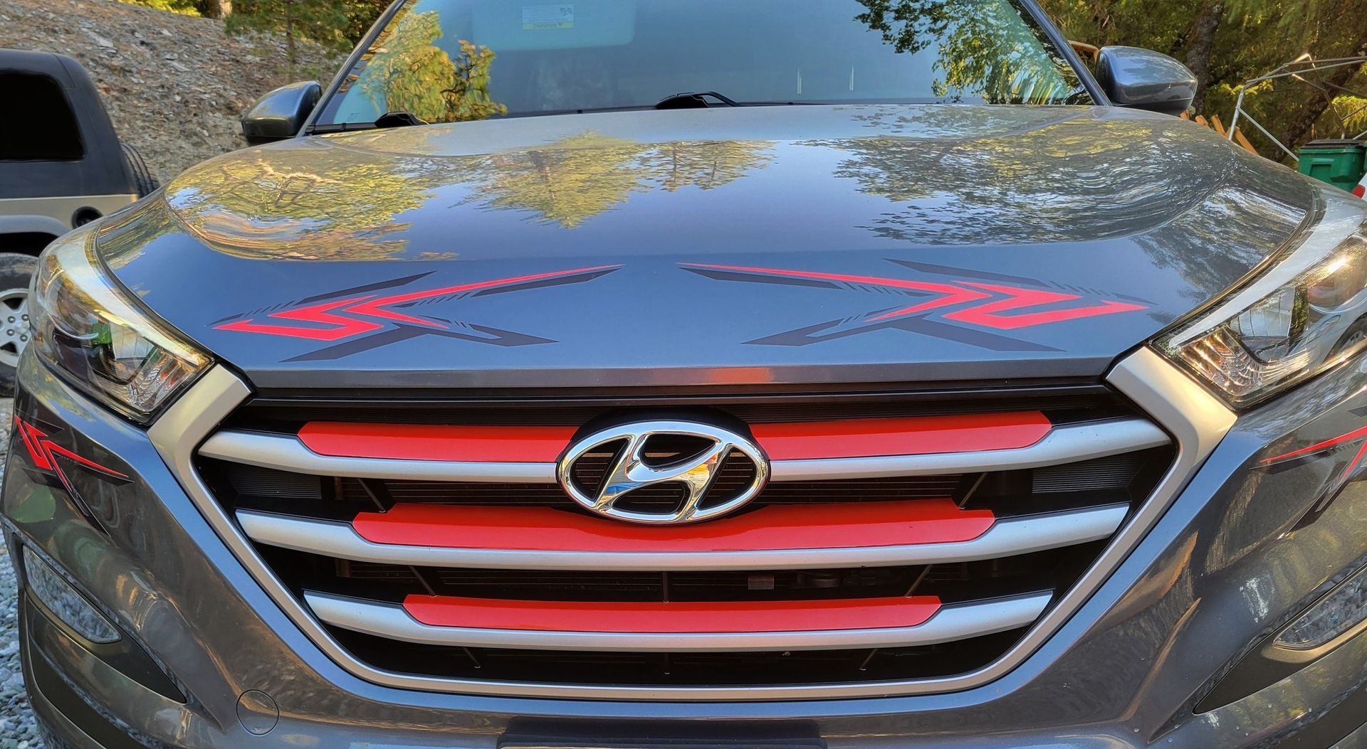 Front view of a gray Hyundai SUV with a red-accented grille and hood graffiti-style markings