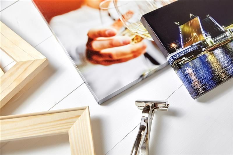 Photo books and wooden frames on a white table, with a silver stapler in the foreground.