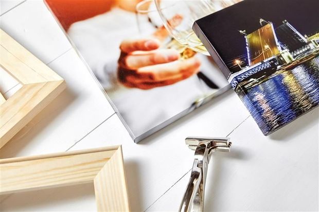 Close-up of printed canvases, wood frames, and a metal razor against a white backdrop.